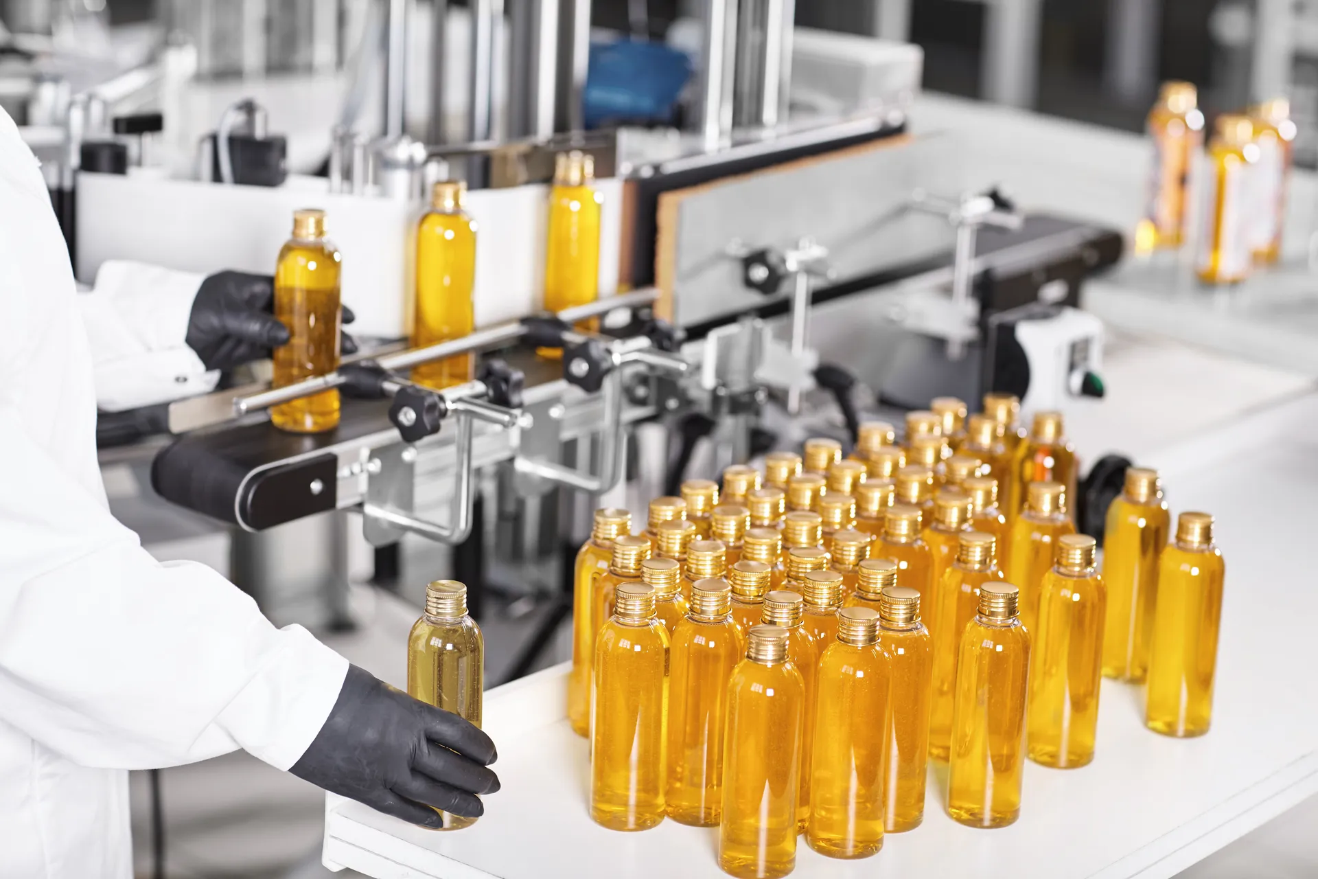 Private's filling line: an operator in a lab coat and gloves inspects freshly filled amber bottles